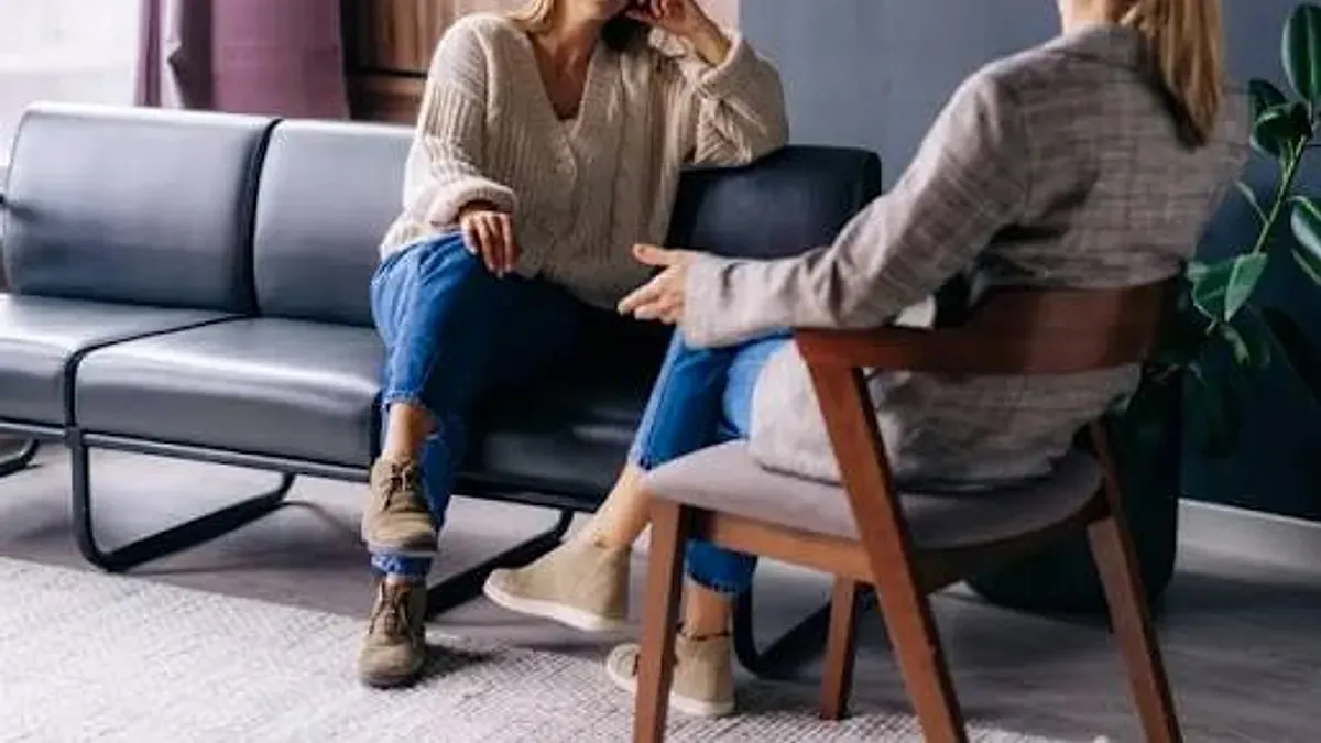 Psikolog ile Psikiyatrist Arasındaki Fark Nedir? konulu görsel: gri kanepede iki kişi bir görüşme yapıyor