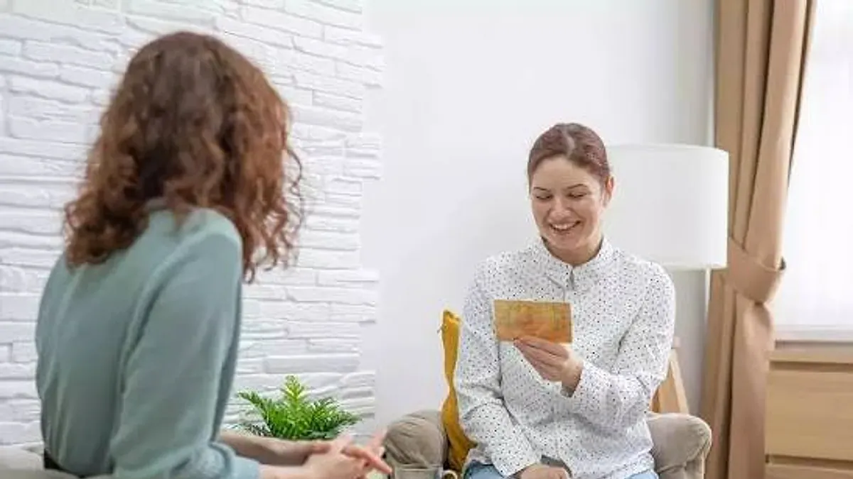 İlk Terapi Seansı Nasıl Geçer? Neler Beklenmeli? konulu görsel: terapide gülümseyen bir danışan ve karşısındaki psikolog