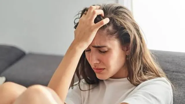 Depresyon Belirtileri Nelerdir? Ne Zaman Psikologa Gidilmeli? konulu görsel: başını elleriyle tutan, üzgün genç bir kadın