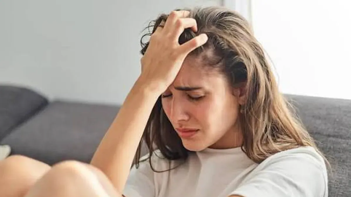 Depresyon Belirtileri Nelerdir? Ne Zaman Psikologa Gidilmeli? konulu görsel: başını elleriyle tutan, üzgün genç bir kadın